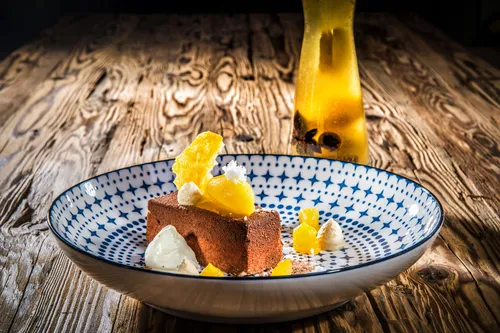 Gourmet-Schokoladendessert mit Mangosorbet und Sahne auf gemustertem Teller
